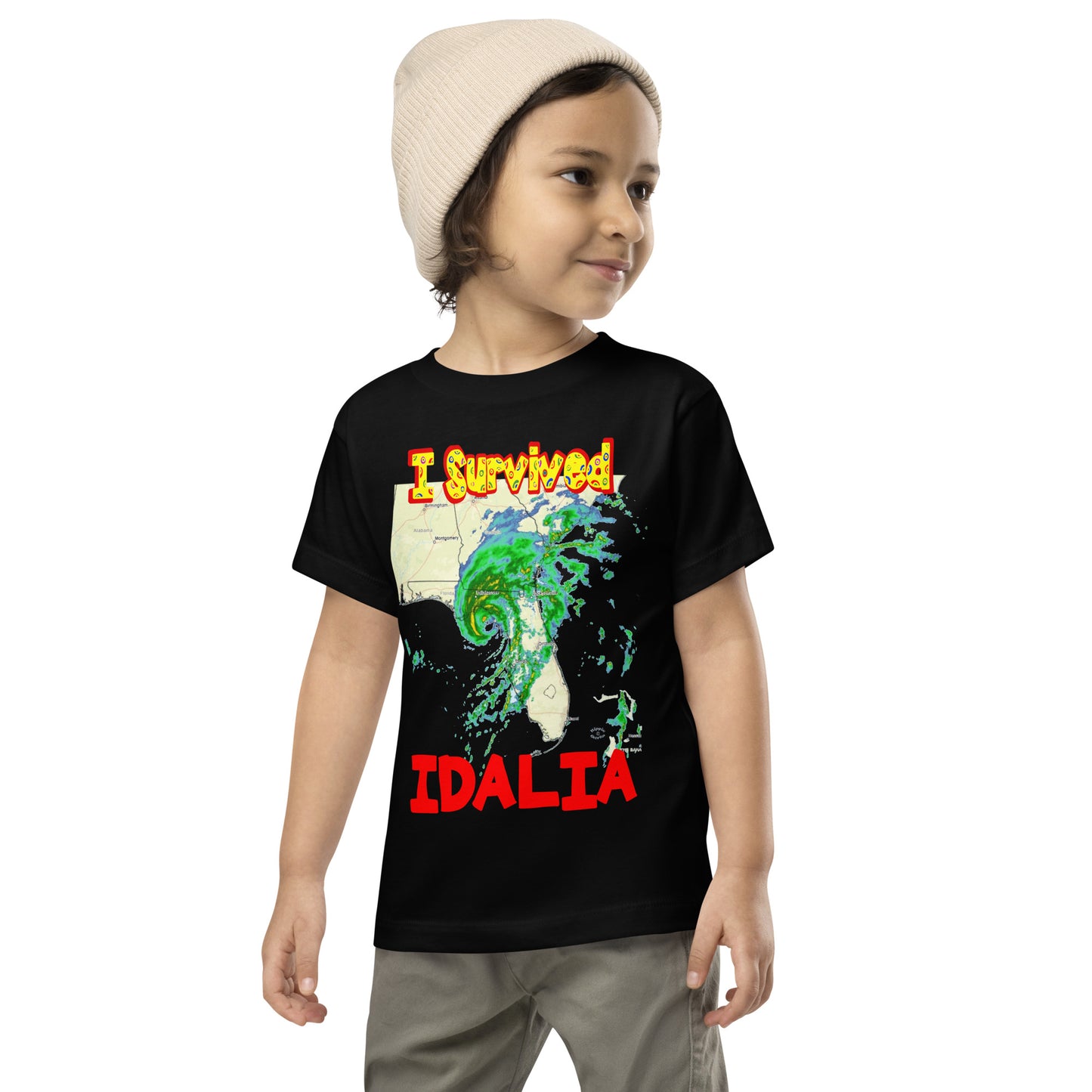 A picture of a little boy wearing a I Survived Hurricane Idalia Toddler Short Sleeve Tee - black