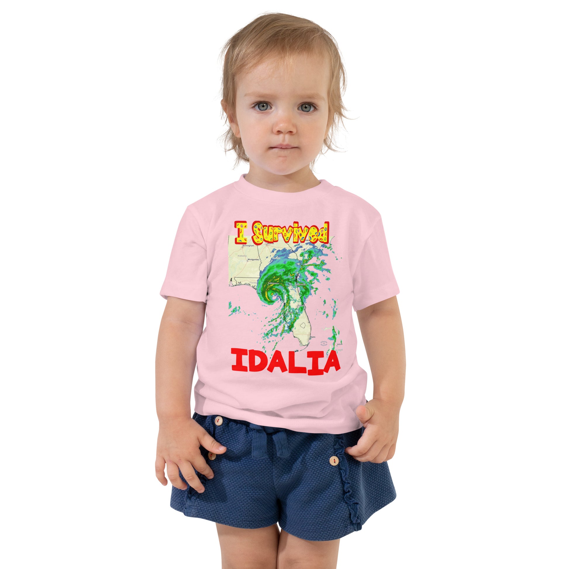 A picture of a little girl wearing a I Survived Hurricane Idalia Toddler Short Sleeve Tee - pink