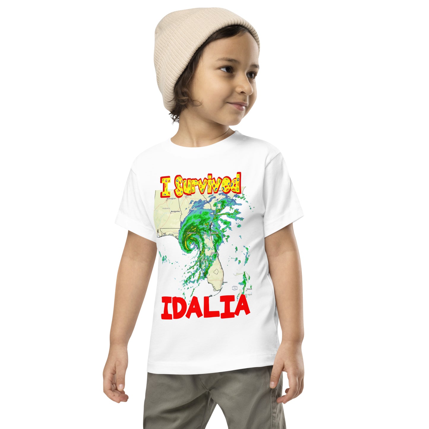 A picture of a little boy wearing a I Survived Hurricane Idalia Toddler Short Sleeve Tee - white