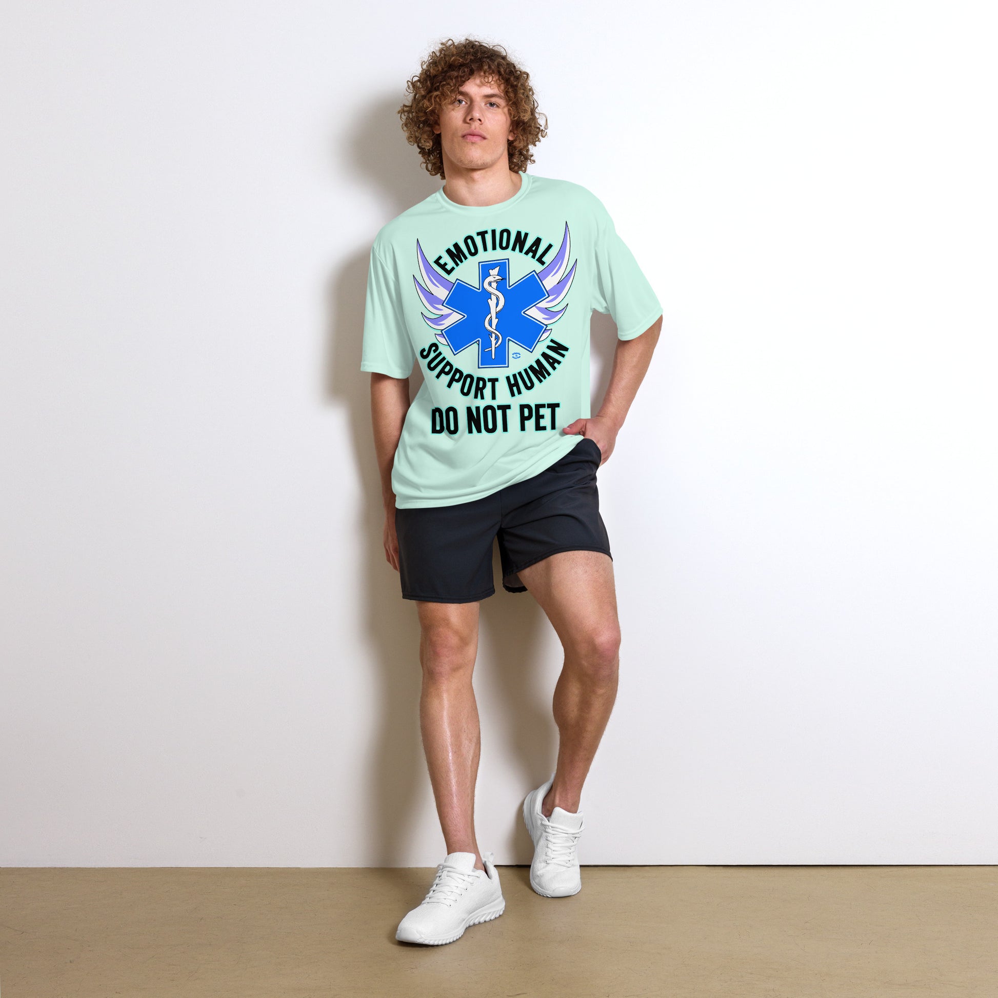 A man wearing a tshirt with a big blue cross and a Rod of Asclepius inside. Text around the cross says Emotional Support Human DO NOT PET - pastel mint