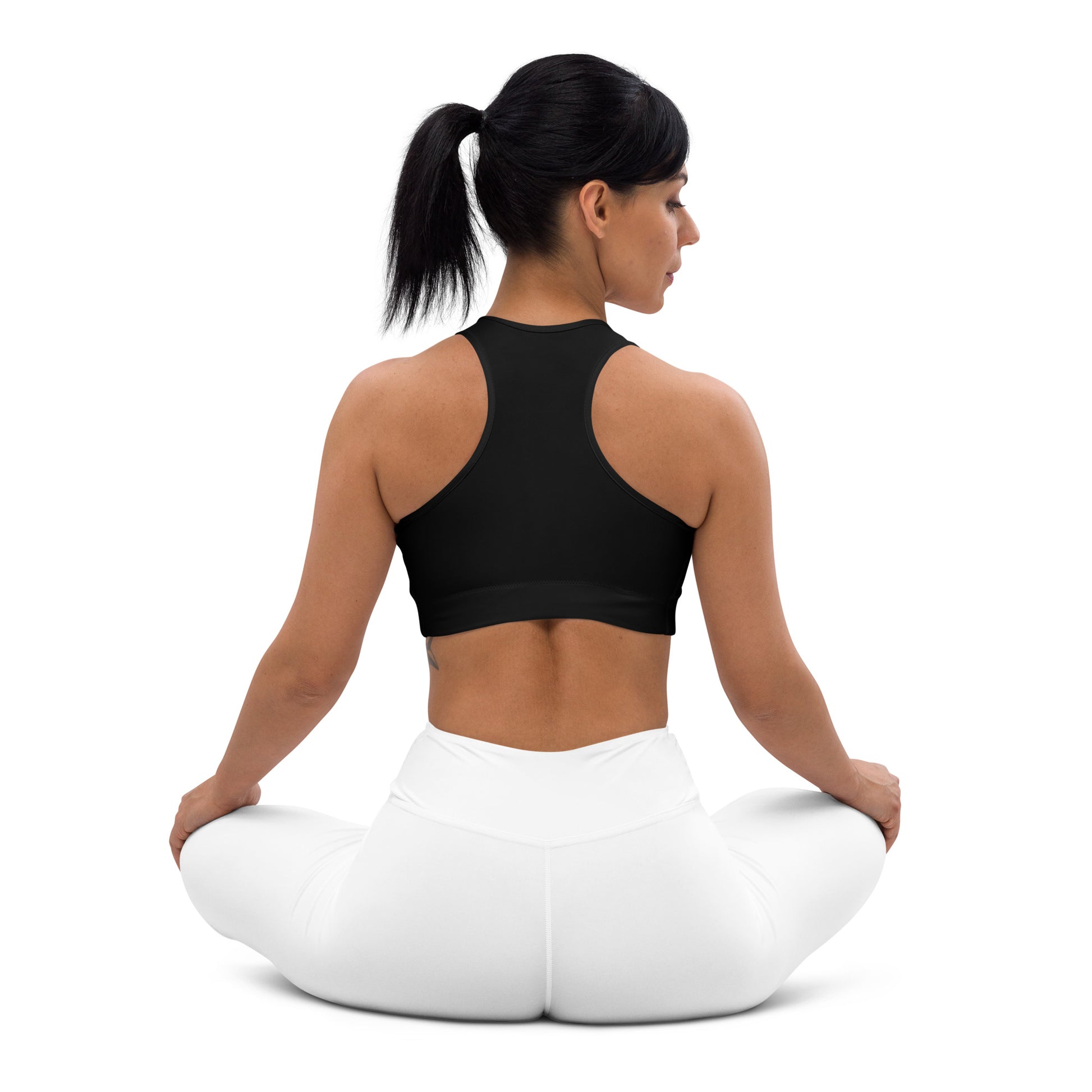 A picture of a women on the floor in a yoga pose wearing a Black padded sports bra - crop top - back side