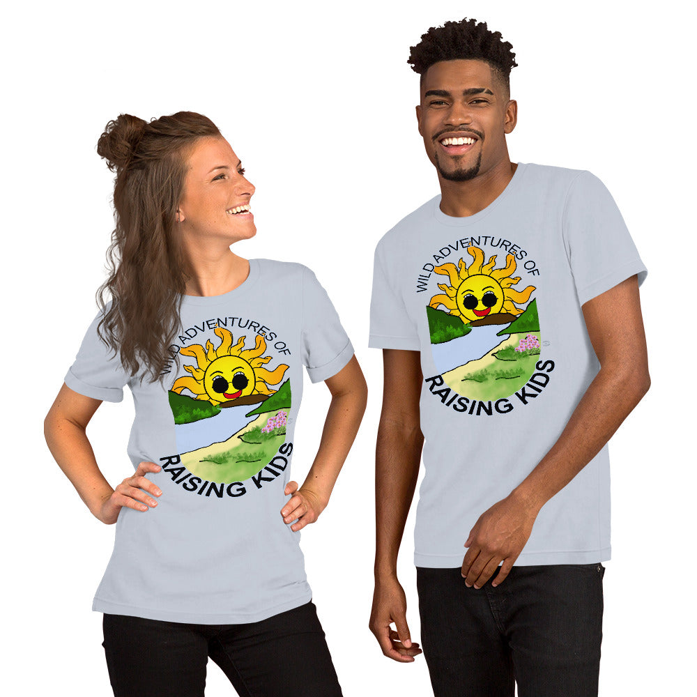 A man and a woman wearing matching tshirts with a picture of the sun coming up over the mountains with sunglasses on and a little stream gently flowing trees and bushes can be seen on the closer mountains and a small beach with some flowers are on the closes bank around the outside of the picture is written "Wild Adventures of Raising Kids" unisex tshirt - light blue front