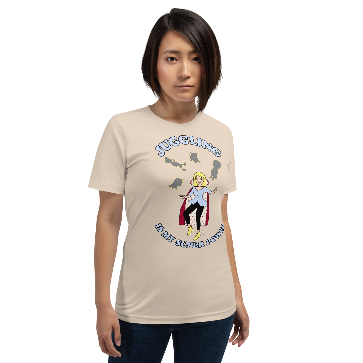 A women wearing a unisex short sleeve tshirt which has on the front a cartoon women in a cape juggling her family like a jester and the text Juggling Is My Super Power - front - soft cream